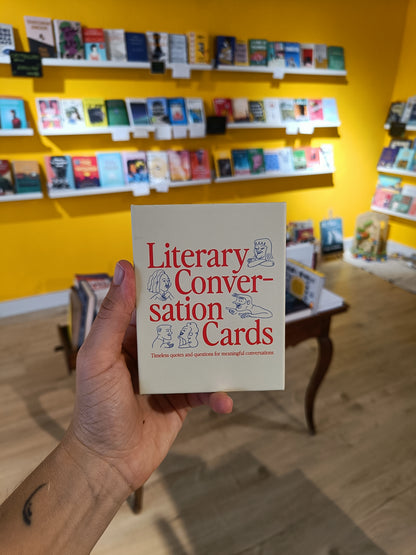 Hand holding 'Literary Conversation Cards' book in a bookstore setting